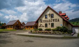 Ośrodek jazdy konnej Michałówka z drewnianymi domkami i głównym budynkiem z napisem "Michałówka".
