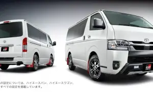 Dwa białe vany Toyota Hiace z pakietem GR Parts. Jeden z tyłu, drugi z przodu, oba z czerwonymi chlapacami.