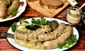 Herzhafte Würste mit Zwiebeln und Petersilie, serviert mit Brot und Dip. Was sind blaue Zipfel? Diese Würste sind ein Genuss!