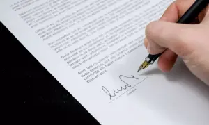 Dłoń podpisuje dokument piórem. Czy akt notarialny jest aktem własności? To pytanie, na które odpowiedź znajdziesz w treści dokumentu.