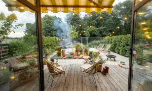 Nowoczesna stodoła z tarasem zaprasza do relaksu. Wygodne fotele, stół z przekąskami i grill tworzą idealne miejsce na letnie wieczory.