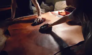 Mani esperte lavorano il cuoio con cura, un processo di lavorazione cuoio artigianale che dona profondità e colore alla pelle.