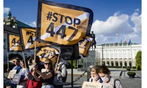 Protestujący trzymają flagi z napisem #STOP 447. Tło stanowi Pałac Prezydencki w Warszawie.