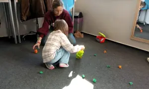 Terapeuta pomaga dziecku w zabawie, która jest częścią wczesnego wspomagania rozwoju.