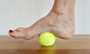 Fuß auf einem Tennisball zur achillessehne dehnen. Sanfter Druck auf die Ferse zur Lockerung.