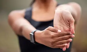 Une personne étire son poignet gonflé, portant une montre connectée.