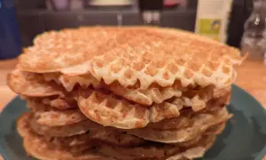 En hög med gyllene, glutenfria våfflor på en grön tallrik. Perfekt för en frukost eller fika.