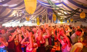 Fröhliche Menschen im Festzelt, die auf einer Veranstaltung in Pasing tanzen und jubeln.