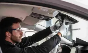 Un technicien porte des lunettes de sécurité et des gants pour démonter le rétroviseur intérieur. C'est le moment pour changer un pare-brise.