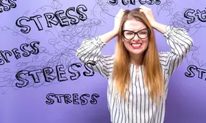 En kvinna med glasögon drar sig i håret, ansiktet förvridet av ansträngning. Orden "stress" är utspridda runt henne, som en visuell representation av hennes arytmi stress.
