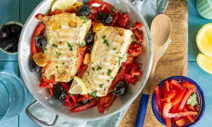 Délicieuse recette cabillaud aux poivrons rouges, olives noires et citron, servie dans un plat en métal.