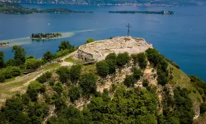 Rocca di Manerba, un sito archeologico con rovine e una croce, domina il lago.
