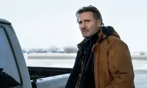 Liam Neeson w brązowej kurtce, w zimowej scenerii, jak w jego filmach.