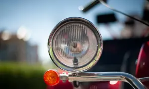 Chromowany reflektor i pomarańczowy kierunkowskaz motoroweru. Czy motorower musi mieć kierunkowskazy? Tak, dla bezpieczeństwa.