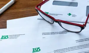Okulary leżą na dokumentach ZUS, wśród których znajduje się wniosek o świadczenie rehabilitacyjne.