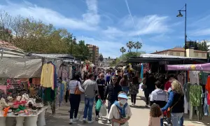 Folkmyller på marknad i Fuengirola. Stånd med kläder och skor längs en solig gata.