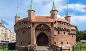 Barbakan w Krakowie, jedna z głównych kraków atrakcje, zaprasza do zwiedzania. Drewniany most prowadzi do zabytkowej budowli.