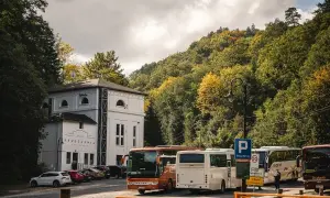 Autobusy czekają przed Starą Kruszarnią w Złotym Stoku. Jesienne drzewa otaczają parking.