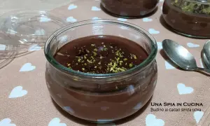 Budino al cioccolato fatto in casa, guarnito con pistacchi tritati, servito in vasetti di vetro su un tovagliolo con cuoricini.