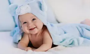 Uśmiechnięty bobas w niebieskim kocyku z misiem.