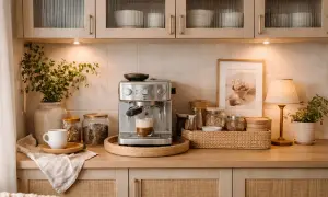 En mysig kaffestation hemma med espressomaskin, kaffebönor i burkar, en vit kopp och en grön växt.
