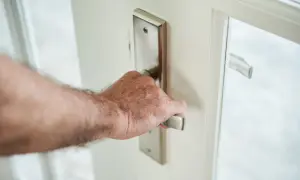 Main d'homme ouvrant une porte blanche, le bruit de la porte qui grince se fait entendre.