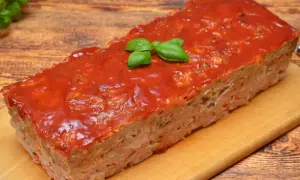 Pieczeń rzymska z sosem pomidorowym i bazylią na desce.