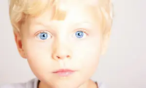 Jasne, błękitne oczy chłopca z blond włosami. Wczesne wykrycie fenyloketonurii jest kluczowe dla jego zdrowego rozwoju.