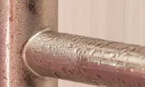 Krople wody na metalowych rurach, efekt pocenia się rur zimnej wody.