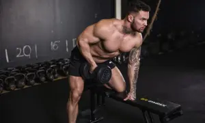 Mann macht ein Workout mit Hanteln auf einer Bank im Fitnessstudio.