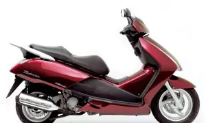 Elegancki, czerwony skuter Honda Pantheon z czarnym siedzeniem i chromowanym bagażnikiem, gotowy na miejskie przygody.