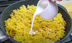 Makaron farfalle z kiełbasą w sosie śmietanowym, gotowany na patelni.