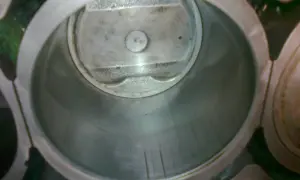 Wnętrze cylindra silnika z widocznym tłokiem. Widać ślady zużycia na ściankach, sugerujące dopuszczalny luz tłoka w cylindrze.