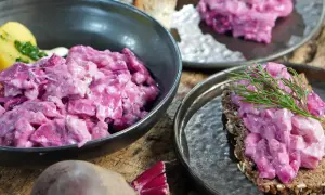 Omas roter Heringssalat, cremig und leuchtend pink, serviert mit Kartoffeln und auf Brot mit Dill.