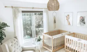 A serene twin m nursery with two wooden cribs, a plush armchair, and whimsical animal art.