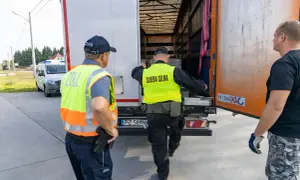 Celnik w kamizelce "Służba Celna" sprawdza ładunek ciężarówki. Chcesz wiedzieć, jak zostać celnikiem na lotnisku? To praca pełna wyzwań!