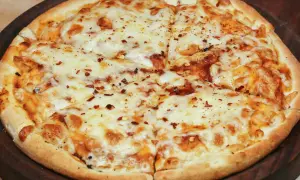 Pyszna pizza bez drożdży, obficie posypana serem i płatkami chili, pokrojona na kawałki.