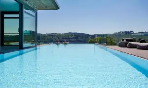 Traumpool mit Blick ins Grüne – perfekter Urlaub in NRW. Zwei Personen genießen das Wasser, während sich im Hintergrund sanfte Hügel erstrecken.