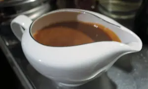 Eine weiße Sauciere gefüllt mit brauner Marsalasauce.