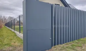 Nowoczesne ogrodzenie z pionowych paneli i słupka z ukrytą skrzynką elektryczną. Czy skrzynka elektryczna musi być w ogrodzeniu? Tutaj jest dyskretnie wkomponowana.
