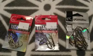 Trzy opakowania haczyków wędkarskich. Dwa z napisem "TITANIUM", jeden z "Kamatsu". Idealne, by złowić karasia.
