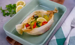 Salmone al cartoccio con patate, pomodorini e limone, pronto per essere infornato.