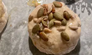 Nybakade glutenfria frallor med pumpa- och solrosfrön på en bakplåt.