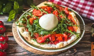 Pizza mit frischen Tomaten, Rucola und einer Kugel Burrata, die Lust auf burrata selber machen macht.