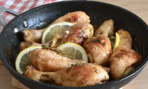 Cosce di pollo al limone succulente e dorate, cotte in padella con fette di limone e erbe aromatiche.