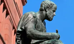 Posąg filozofa, który zgłębia tajniki bytu i ontologii, siedząc z piórem w dłoni.