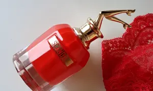 Czerwony flakon perfum Scandal EDP z złotymi nogami i koronkową bielizną. Zapach budzi skojarzenia z odwagą i zmysłowością.