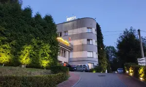 Elegancki hotel Izabella w Puławach, otoczony zielenią i oświetlony wieczorem. Zaprasza do odpoczynku.