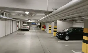 Wrocław główny parking cennik: podziemny parking z białym i czarnym Volkswagenem, białym BMW, rurami i klimatyzacją.