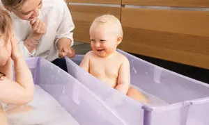 Glad bebis i badbalja, en mamma tittar på. Frågan "hur ofta bada bebis" kan besvaras med att det är mysigt att bada ofta!